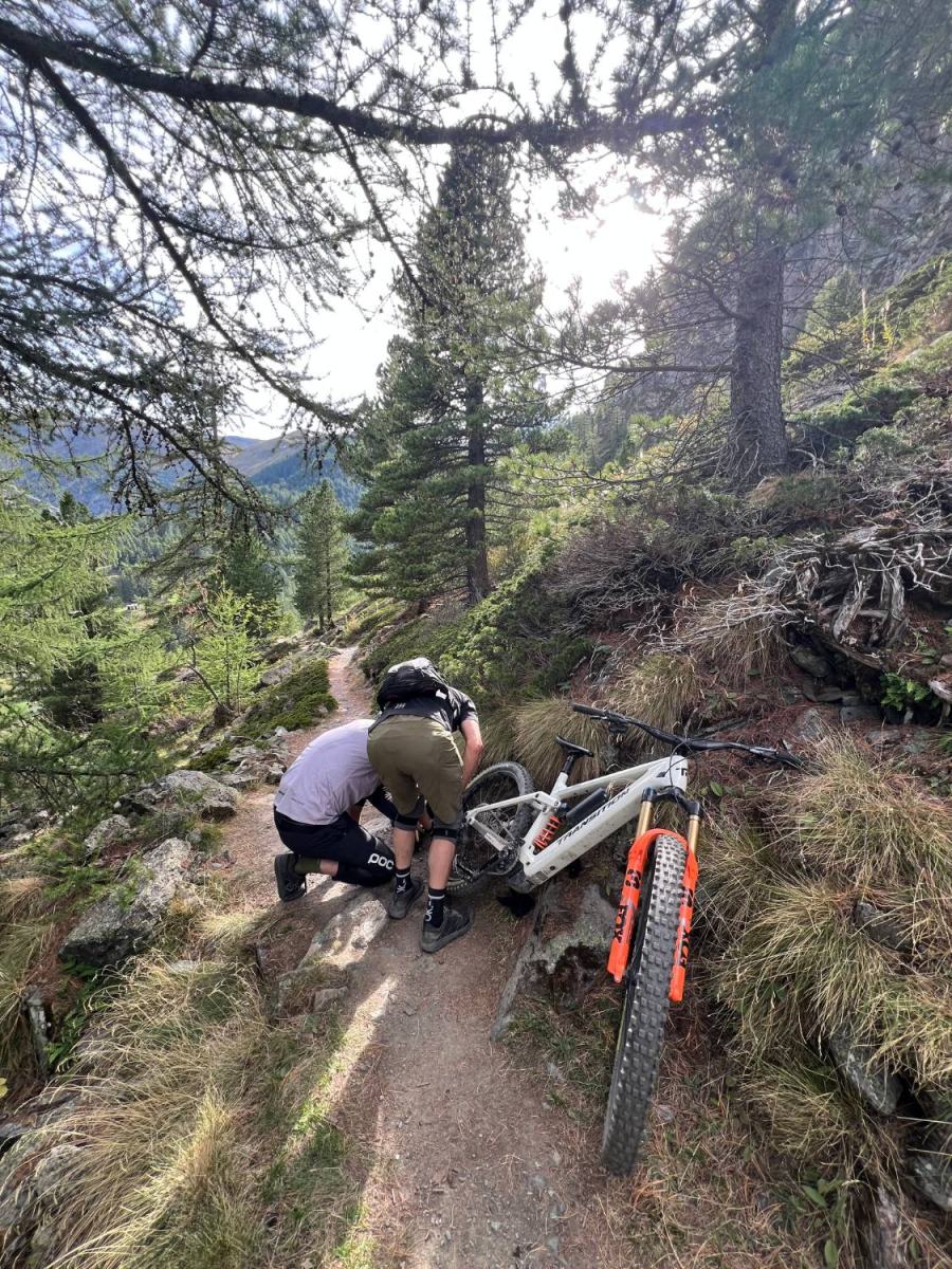 Two mountain bikers repairing a bike on the trail itself during a shuttle day in Valais