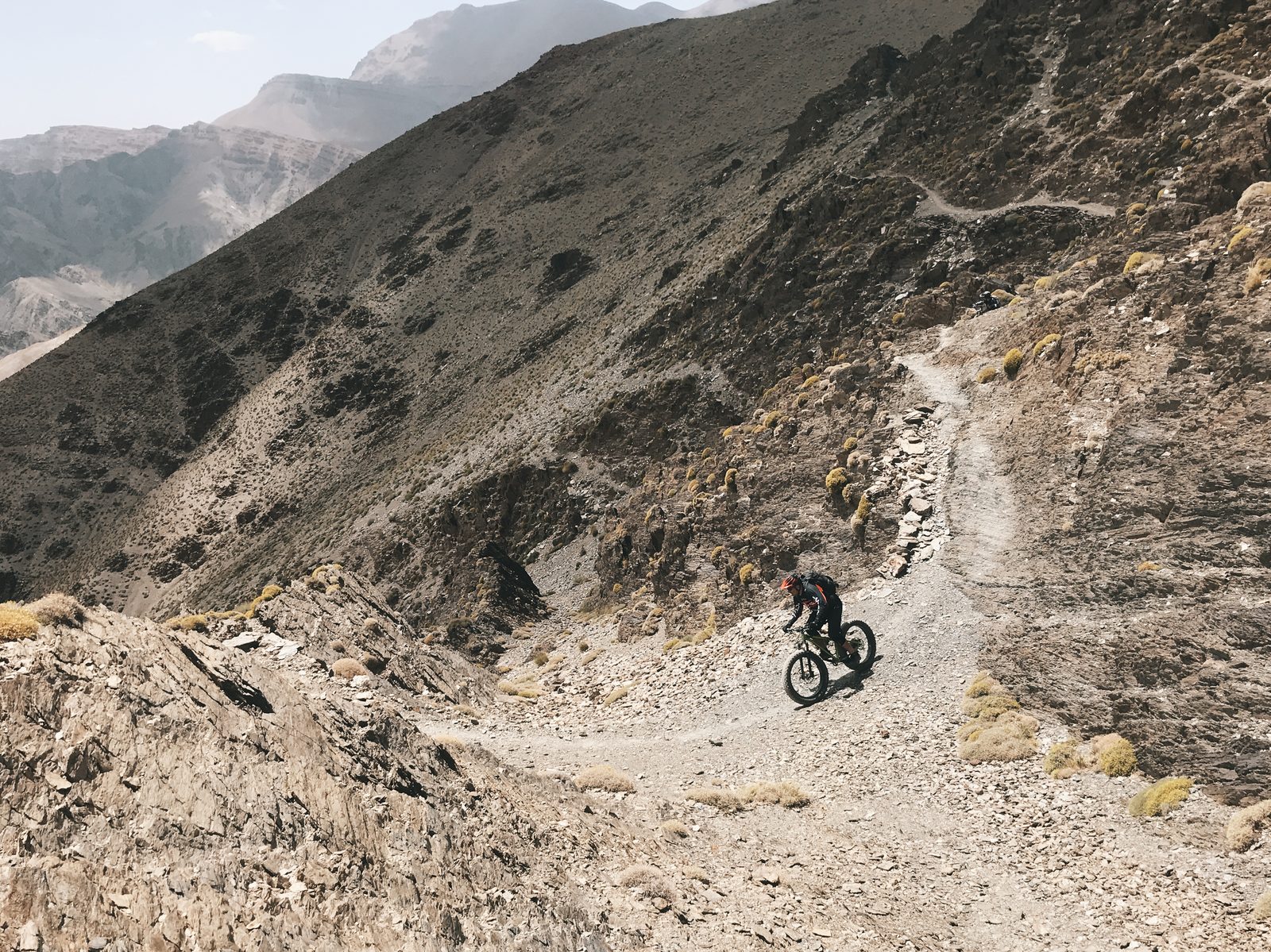 Un rider sur un sentier rocheux en lacets dans le Haut-Atlas marocain, préparer son séjour VTT avec Exoride