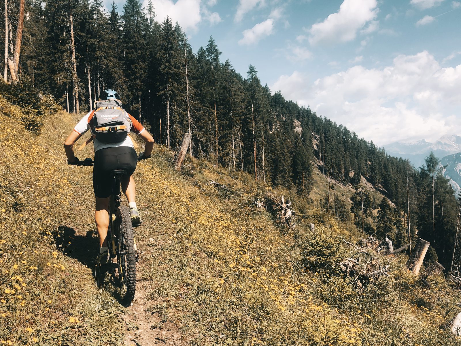 Un rider monte à son rythme sur un sentier en forêt, en Valais, préparer son séjour VTT avec Exoride