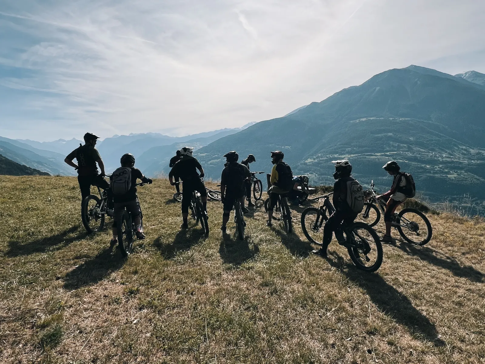 A crew of Exoride riders from behind, on a ridge facing the mountains