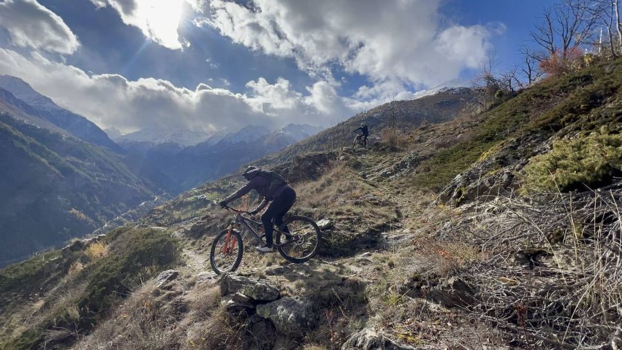 Zwei Rider auf einem Balkontrail vor verschneiten Gipfeln, Herbst im Wallis